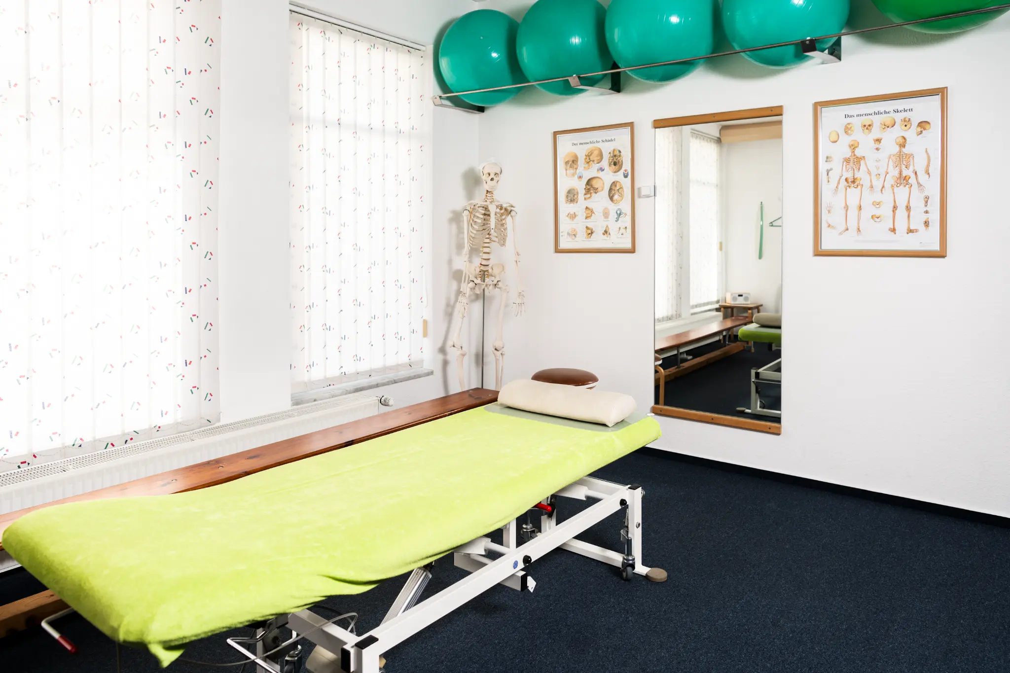 Heller Behandlungsraum mit großen Fenstern und Trainingsgeräten